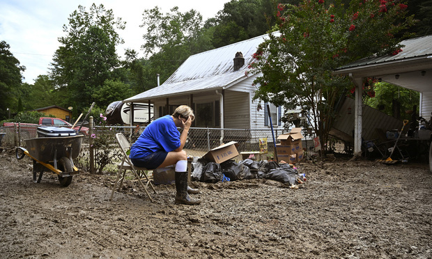 Teresa Reynolds sits exhausted as members of her community clean the debris from their flood-ravaged homes at Ogden Hollar in Hindman, Ky., Saturday, July 30, 2022. (Credit: Timothy D. Easley/AP) 