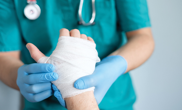Nurse bandaging a person's injured hand.