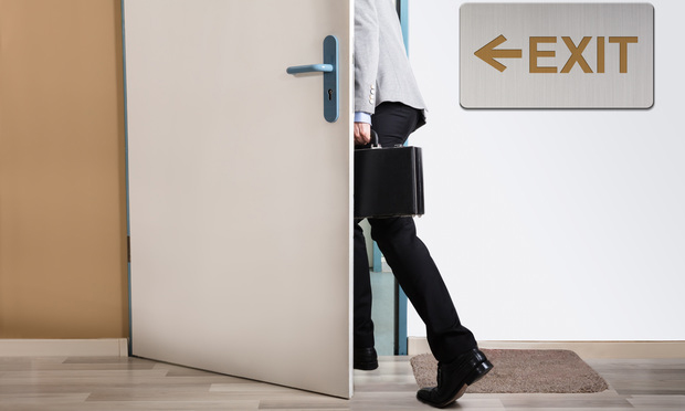 Businessperson Walking Out With Exit Sign On Wall // Shutterstock