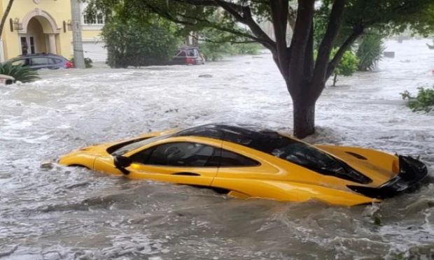 A yellow sports car is submerged in flood waters.
