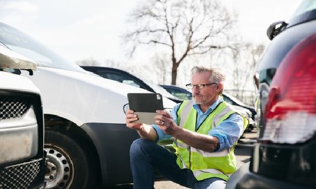 Person using technology to assess damage from a car accident.