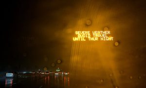 A weather warning sign beside the freeway during a rain storm in Los Angeles, on Thursday, Jan. 5, 2023. A powerful storm with hurricane-force gusts has begun to wind down after ripping across California, leaving behind power outages, flood threats and road closures just hours before another drenching is set to wash over the state. (Credit: Eric Thayer/Bloomberg)