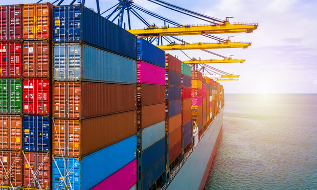 A ship with brightly colored shipping containers sails on a body of water.