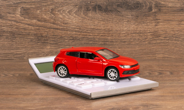 A red toy car on top of a calculator.