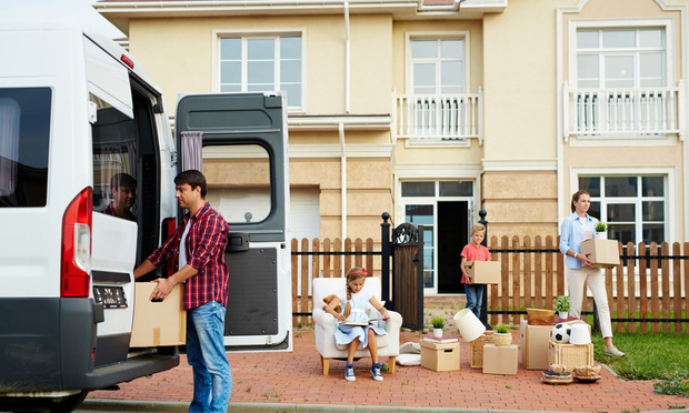 A family carriers moving boxes from a van to their home.