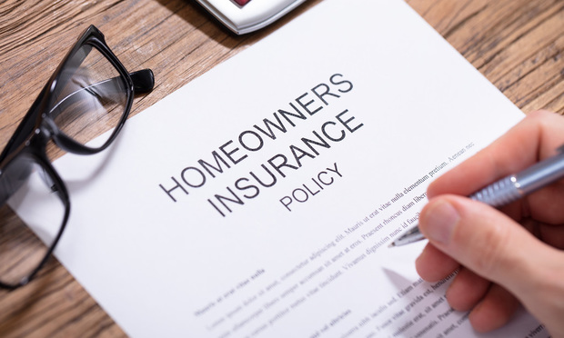 Overhead view of a person signing a homeowners insurance document.