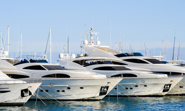 A row of several white yachts, docked in a row.