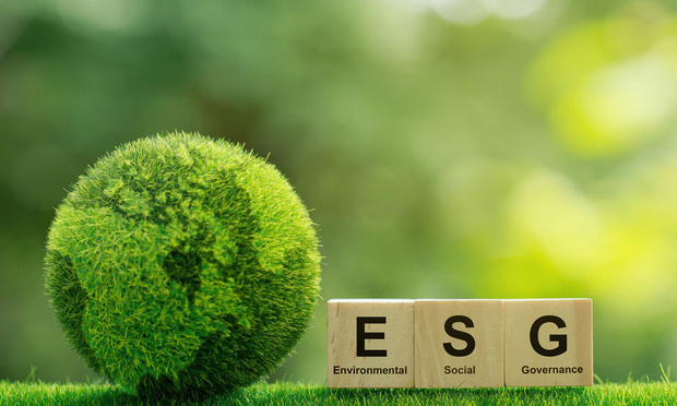 Wooden blocks that spell "ESG" sit next to a globe made out of greenery