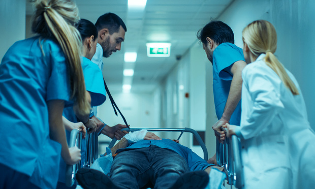 Physicians and nurses tending to a person on a stretcher in the emergency department.