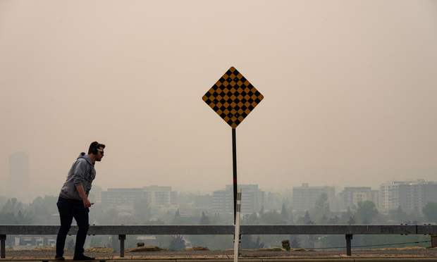 A skateboarder passes buildings shrouded in smoke from wildfires in Calgary, Alberta, Canada, on Wednesday, May 17, 2023. 