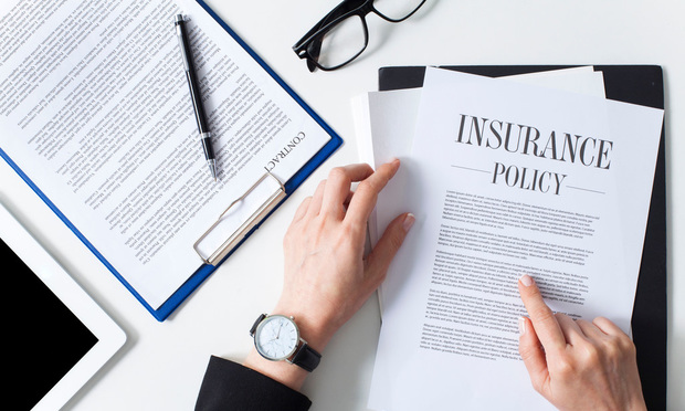 A photo focused on a person's hands as they sign an insurance policy