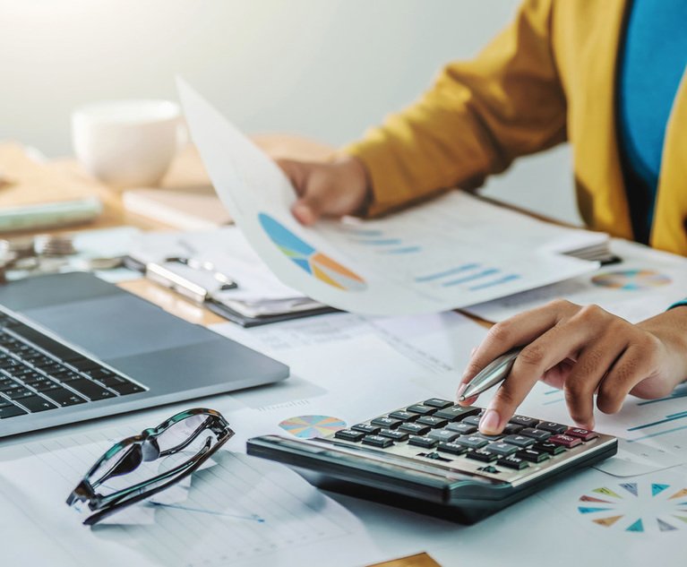 A person uses a calculator at their desk while working.