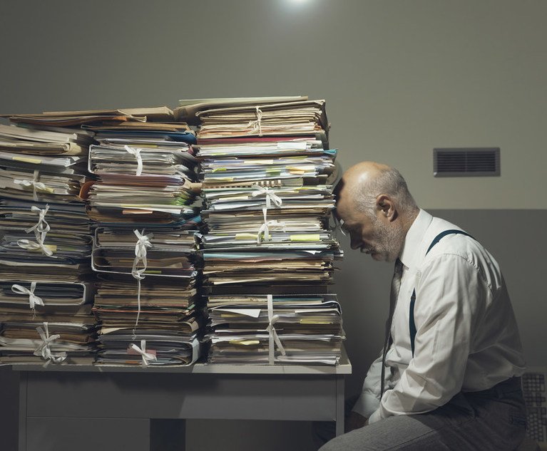 Depressed businessman with files stacked on a desk
