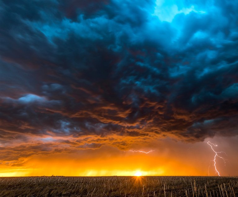 A nighttime, tornadic mezocyclone lightning storm shoots bolt of electricity to the ground and lights up the field and dirt road in Tornado Alley.