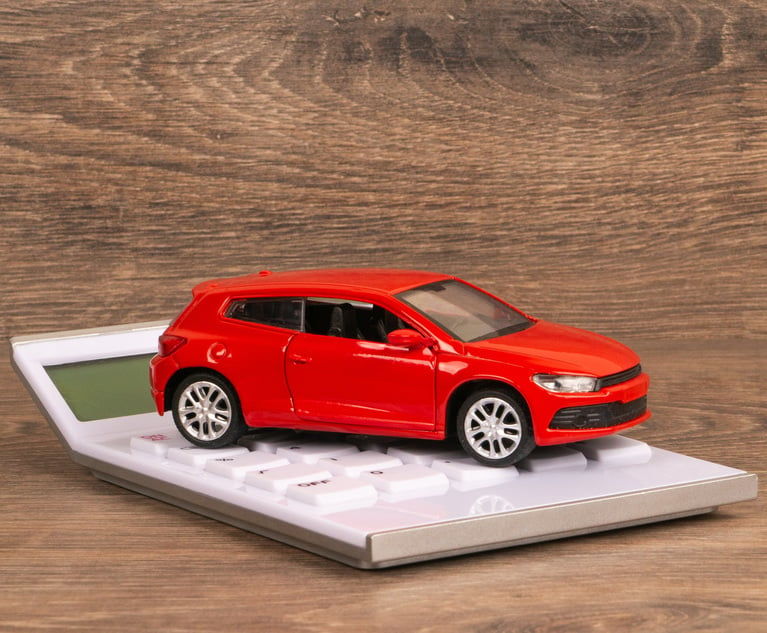 A red toy car sits on top of a calculator.
