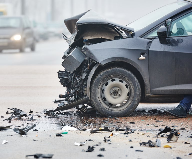 A car with a wrecked front sits in the road.