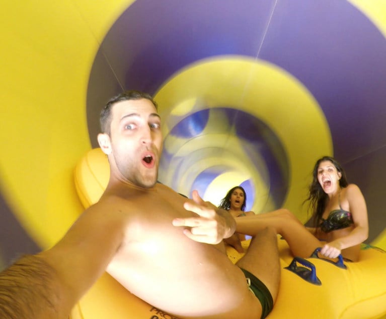 Three people take a photo as they go down a water slide