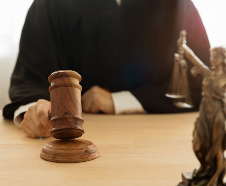 A judge sitting at a desk holding a gavel.