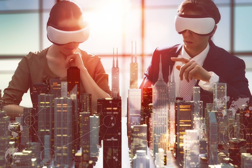 Two business people wearing virtual reality glasses looking at 3d model of buildings