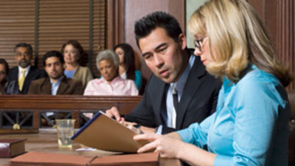 Woman attorney looking at note pad in courtroom with client